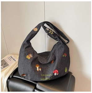 Détails de champignons et escargots brodés sur un sac hobo en jean bleu foncé