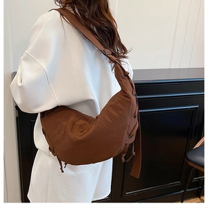 Detail of adjustable strap and drawstring design on brown crescent canvas crossbody bag