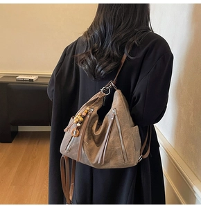 Brown vintage suede tote bag with fringe details worn by a model in a black coat
