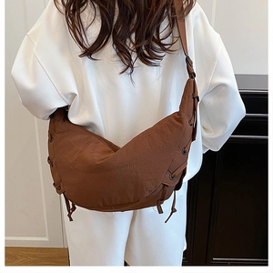 Brown nylon crescent bag shown on model featuring industrial eyelet detail and strap