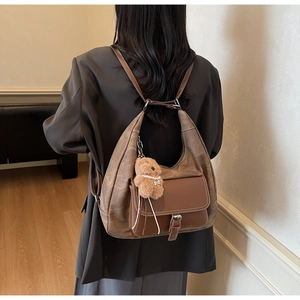 Dettaglio borsa tote in pelle marrone con fibbia in metallo e ciondolo a forma di orso