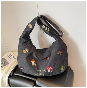 Détail de la broderie forêt sur un sac hobo en denim bleu marine avec motifs floraux