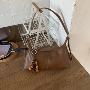 Detailansicht der braunen sichelförmigen Schultertasche mit Vintage-Holzperlenanhänger
