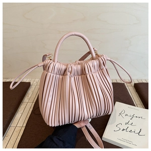 Detail view of pink pleated bucket bag with round handle on a minimalist background