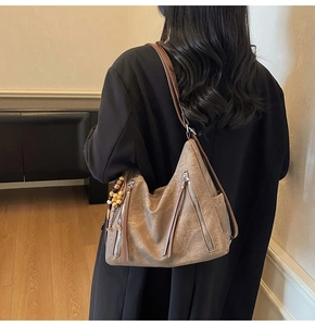 Detail of retro brown leather shoulder bag with tassels and beaded charm on model