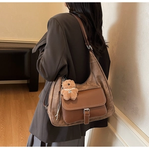 Dettaglio borsa tote marrone vintage con tasca a contrasto e ciondolo a orsetto
