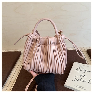 Detailed shot of soft pink pleated bucket bag with matte leather finish and drawstring