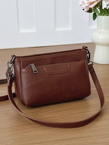 Minimalist brown crossbody bag in vintage style with adjustable shoulder strap and front zip pocket
