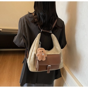 Dettaglio della borsa hobo con tasca in pelle marrone e ciondolo a orsetto su modella