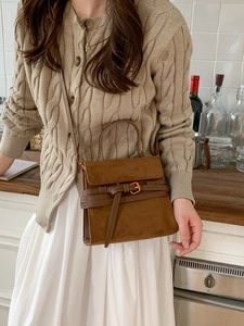 Bolso vintage de ante sintético marrón con hebilla y correa llevado por una modelo