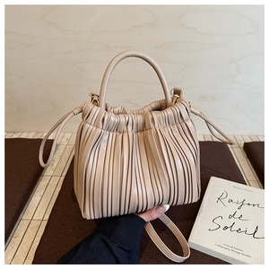 Close-up of beige pleated faux leather bucket bag with textured ruffle finish