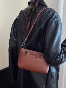 Brown minimalist leather shoulder bag with vintage stitching shown on model back