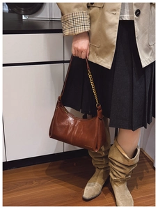 Detail of brown faux leather shoulder bag with gold metal chain strap and zip closure