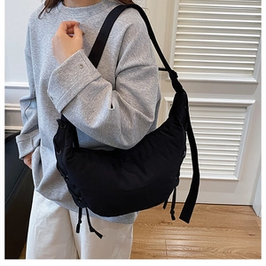 Detail of adjustable strap and drawstring pleats on the black crescent crossbody bag