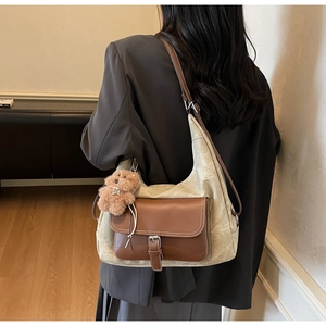 Dettaglio borsa tote in tela vintage con tasca in pelle marrone e ciondolo orso
