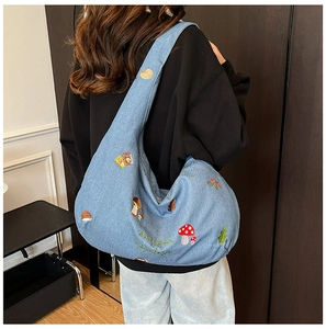 Détail du sac en jean bleu clair avec broderie de forêt et motifs de champignons et hérissons