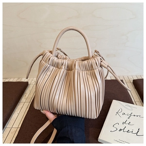 Detailed close-up of beige pleated bucket bag with soft leather texture and handle