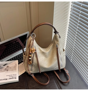 Detail view of a beige retro tote bag with brown straps and wooden bead accessory