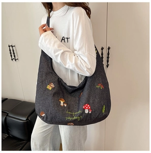 Détail du sac fourre-tout gris en toile avec broderie de champignons colorés et texte art