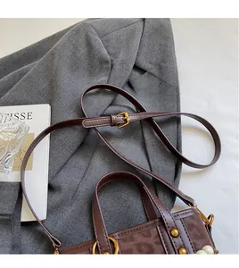 Macro shot of brown retro bucket bag with adjustable strap and gold metal hardware