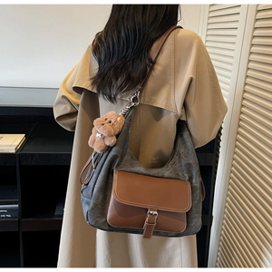Dettaglio borsa hobo con ciondolo a orsetto di peluche e tracolla in pelle regolabile