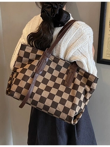 Brown checkered knit tote bag with leather handles shown in a minimalist studio setting