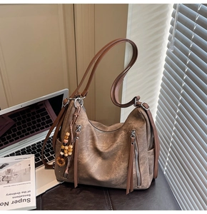 Detail of vintage brown leather hobo bag with zip pockets and wood bead tassel charm