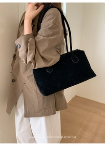 Minimalist large black suede tote bag with slim shoulder straps shown on a model