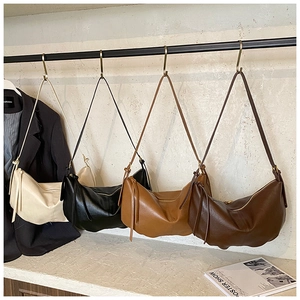 Macro shot of stylish hobo tote bags in four colors hanging in a minimalist studio setting