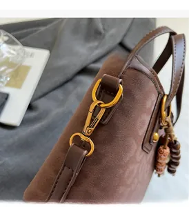 Detailed close-up of premium gold lobster clasp and vintage beads on brown suede bucket bag