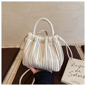 Detailed view of cream-white pleated handbag with vertical ruffles and round handle