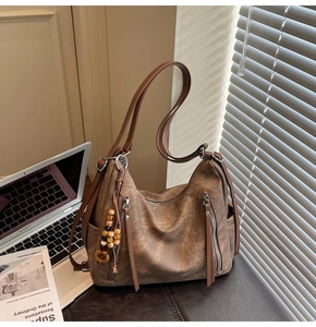 Detail of vintage brown suede tote bag with metal zippers and wooden bead tassel