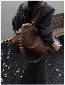 Detail of dark brown Boston bag with stylish wide woven shoulder strap on model