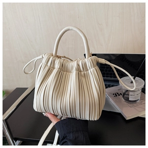 Detail of pleated bucket bag with top handle and strap in creamy white finish