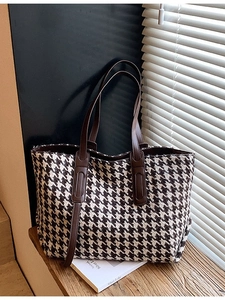 Classic houndstooth tote bag with leather handles on a rustic wooden table background