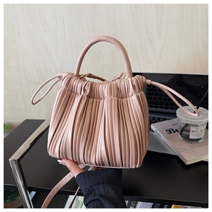 Detail of pink pleated bucket bag with gold hardware and removable strap in office setting