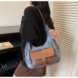 Dettaglio della borsa tote in denim grigio-blu con tasca in pelle marrone e orsetto