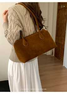 Retro brown suede shoulder bag worn with a beige sweater for a minimalist aesthetic