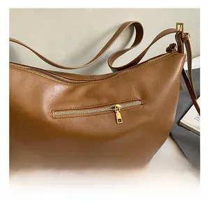 Detailed view of the brown crescent bag featuring pebbled texture and gold zipper hardware