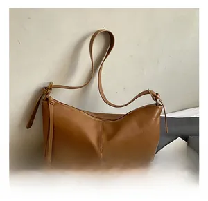 Detail view of the brown crescent bag's smooth faux leather texture and adjustable strap