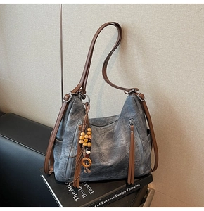 Detail of vintage gray washed tote bag with vertical zippers and ethnic tassel charm