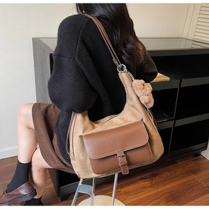 Dettaglio borsa tote con texture scamosciata, tasca in pelle e ciondolo a forma di orso