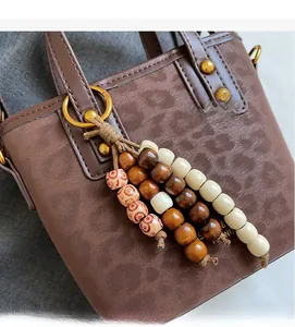 Close-up of brown textured leather bucket bag with wooden bead tassel and gold hardware