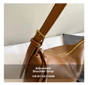 Detail of adjustable shoulder strap with golden buckle on a brown vintage hobo bag