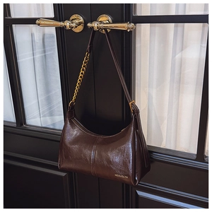 Detailed close-up of dark brown oil wax leather handbag with elegant gold chain and zipper