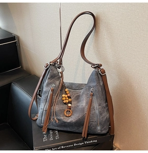 Detail of grey vintage hobo bag with brown straps and vertical zippers on books