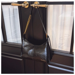 Detailed macro view of black PU leather texture with gold chain on crescent hobo bag