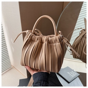 Detailed view of the pleated beige bucket bag with round handle and glossy leather texture