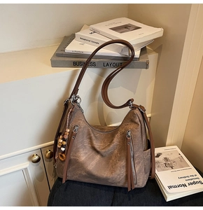 Detail of vintage brown leather shoulder bag with zipper pockets and beaded charm