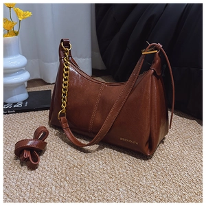 Detail of caramel brown faux leather bag with gold chain and side logo engraving